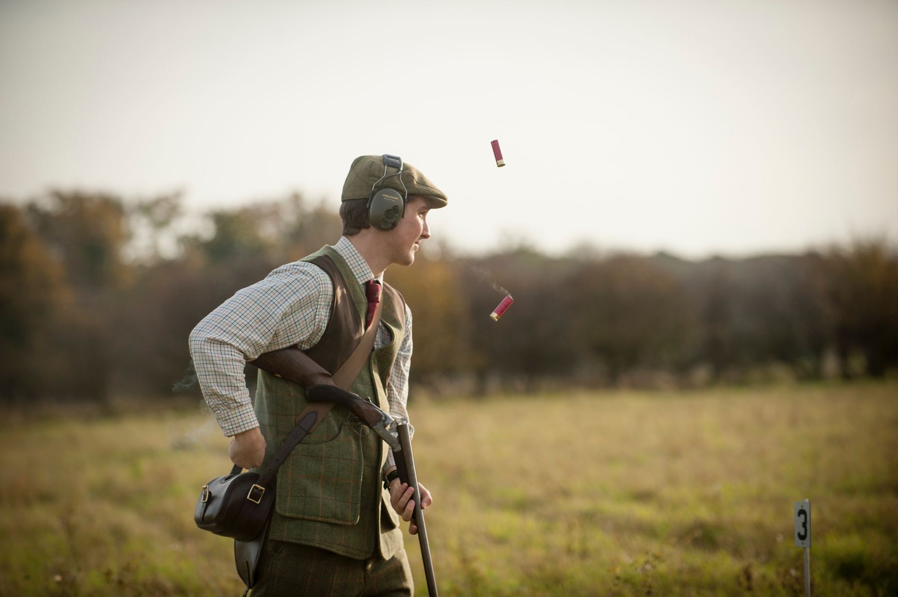 A young gun ejecting two red cartridges at peg three on a driven clay day