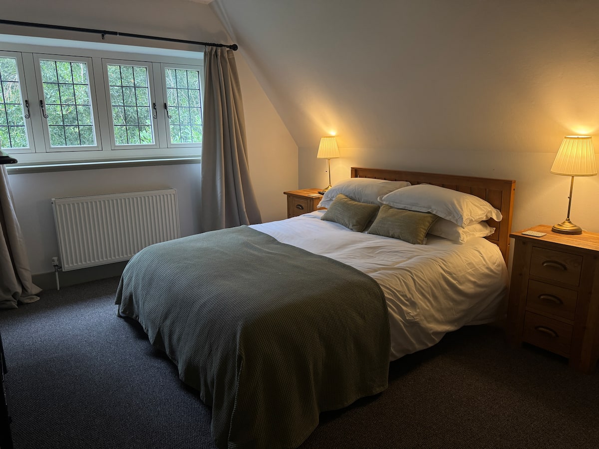 A bedroom under the eaves with a wooden bed and a garden window
