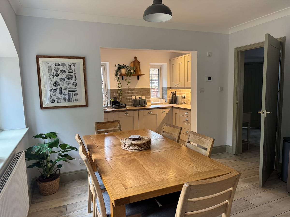 An oak dining table with the kitchen beyond